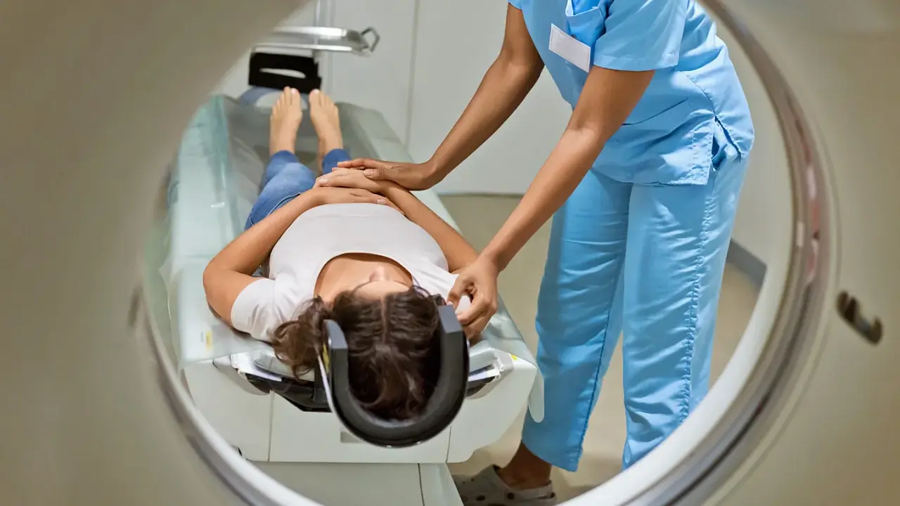 Eine Patientin liegt für eine MRT Untersuchung auf einer Liege, während eine medizinische Fachkraft sie vorbereitet.