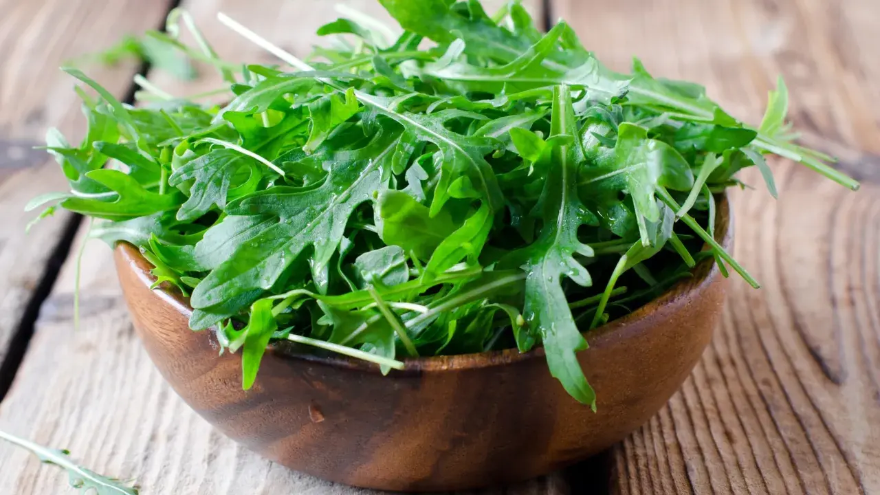 Frischer Rucola in einer Holzschale, bereit für einen gesunden Salat.