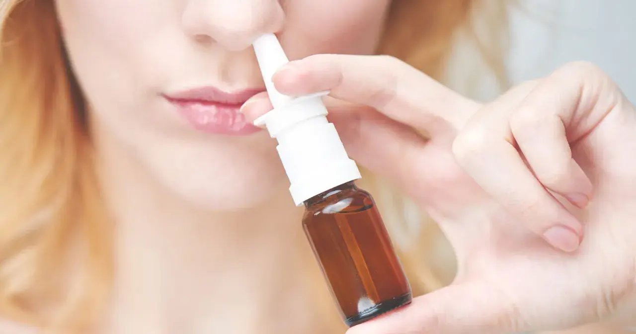 Frau benutzt Nasenspray. Möglicher Geruchsverlust durch Nasenspray.