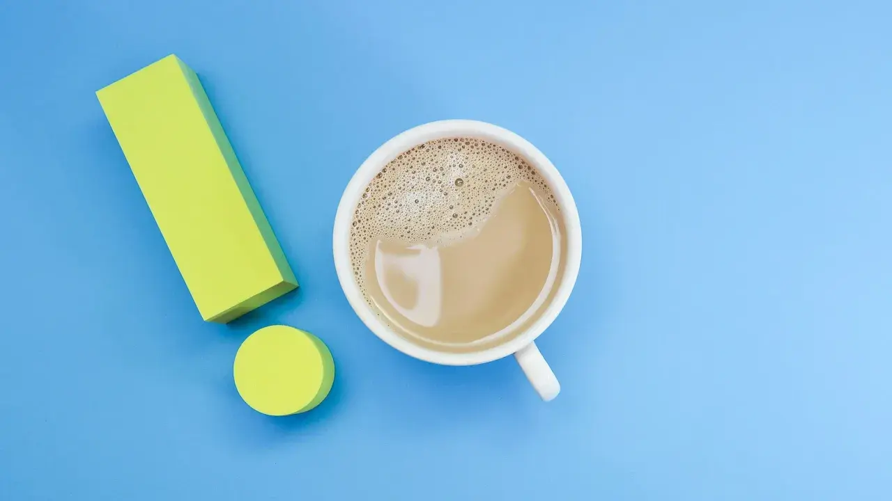 Ein Ausrufezeichen aus gelben Blöcken neben einer Tasse Kaffee. Ein starker Kaffee für einen energiegeladenen Tag, vielleicht mit einem Hauch von Lithium für extra Power.