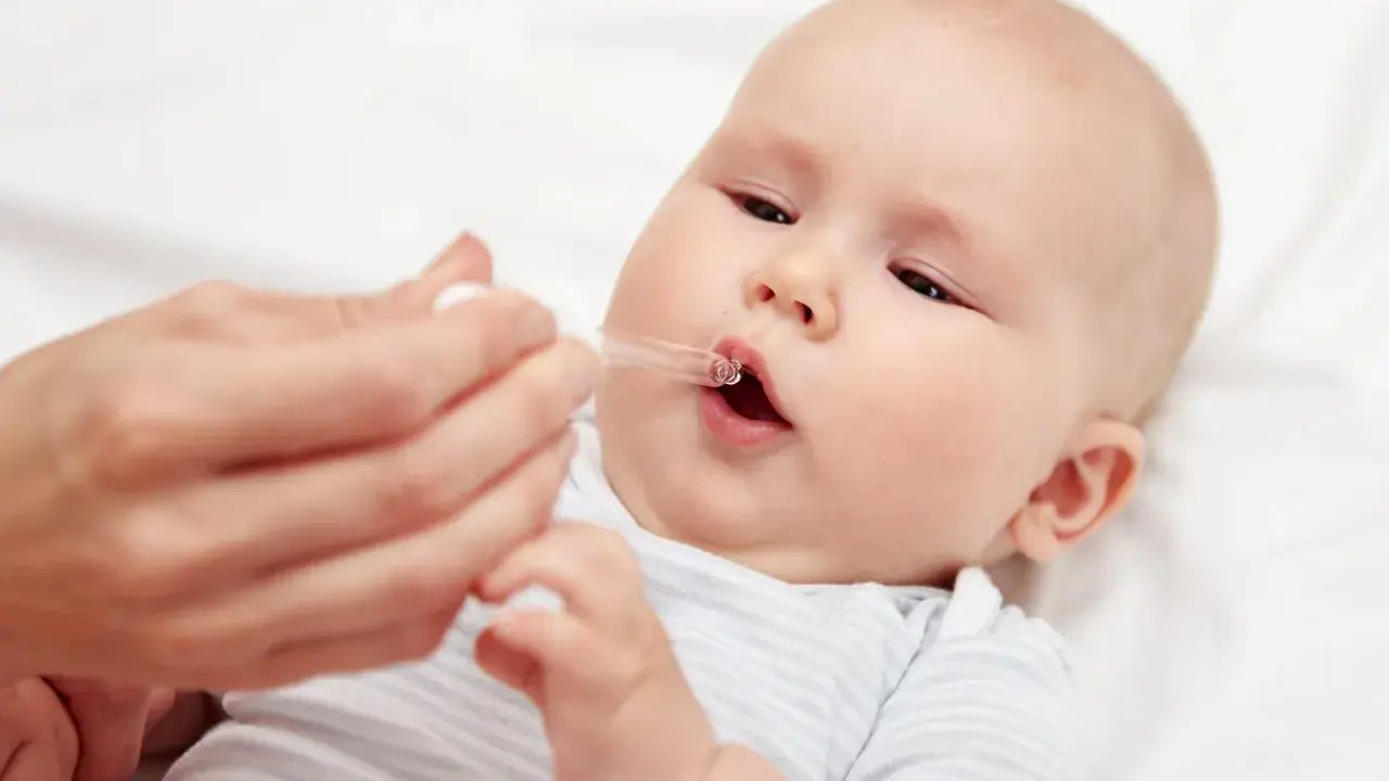 Ein Baby erhält Tropfen mit Vitamin D und Fluorid.