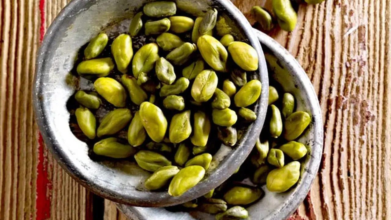 Grüne Pistazienkerne in zwei Schalen auf Holzuntergrund. Diese gesunden Pistazien sind ein leckerer Snack.