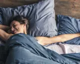 Frau streckt sich im Bett. Wenn man nicht schlafen kann, hilft es manchmal, sich zu bewegen.
