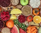Vielfalt an ballaststoffreichen Lebensmitteln: Bohnen, Quinoa, Beeren, Obst, Gemüse und Nüsse für eine gesunde Ernährung.