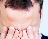 Mann mit Händen vor dem Gesicht, Stirn gerunzelt, als ob er den **exitus letalis** fürchtet.