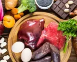 Eine Auswahl an eisenhaltigen Lebensmitteln: Rindfleisch, Leber, Blutwurst, Eier, Linsen, Rote Bete, Spinat, Brokkoli, Aprikosen, Schokolade und Vollkornbrot.