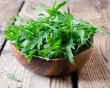Frischer Rucola in einer Holzschale, bereit für einen gesunden Salat.