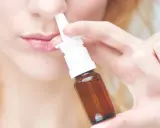Frau benutzt Nasenspray. Möglicher Geruchsverlust durch Nasenspray.