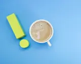Ein Ausrufezeichen aus gelben Blöcken neben einer Tasse Kaffee. Ein starker Kaffee für einen energiegeladenen Tag, vielleicht mit einem Hauch von Lithium für extra Power.