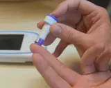 Person hält Lanzette bereit, um den Blutzucker zu messen. Das Messgerät liegt daneben, bereit für den inr wert.