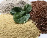 Haufen von Couscous, Buchweizen und Haferflocken, garniert mit frischen Spinatblättern. Ist Couscous gesund? Ja, es ist eine gute Quelle für Ballaststoffe.
