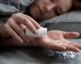 Eine Person nimmt Amitriptylin zum Schlafen ein. Mehrere weiße Pillen liegen auf der Handfläche.