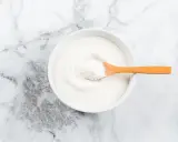 Weißes Kollagenpulver in einer Schale mit Holzlöffel. Die Wirkung von Kollagen für Haut und Gelenke wird oft diskutiert.