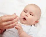 Ein Baby erhält Tropfen mit Vitamin D und Fluorid.