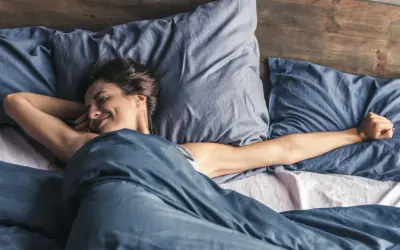 Frau streckt sich im Bett. Wenn man nicht schlafen kann, hilft es manchmal, sich zu bewegen.
