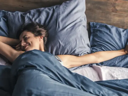 Frau streckt sich im Bett. Wenn man nicht schlafen kann, hilft es manchmal, sich zu bewegen.