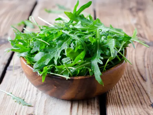 Frischer Rucola in einer Holzschale, bereit für einen gesunden Salat.
