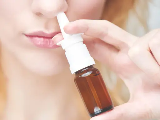 Frau benutzt Nasenspray. Möglicher Geruchsverlust durch Nasenspray.