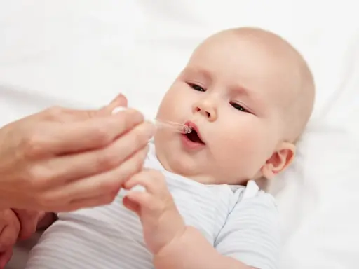 Ein Baby erhält Tropfen mit Vitamin D und Fluorid.