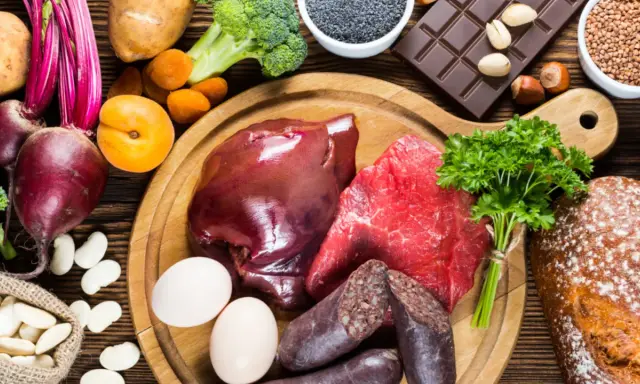 Eine Auswahl an eisenhaltigen Lebensmitteln: Rindfleisch, Leber, Blutwurst, Eier, Linsen, Rote Bete, Spinat, Brokkoli, Aprikosen, Schokolade und Vollkornbrot.