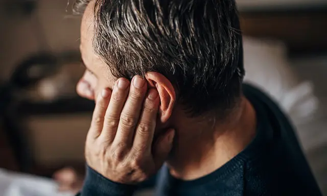 Mann hält sich die Hand ans Ohr, als ob er nicht wüsste, was er tun soll.