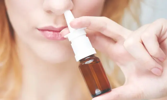 Frau benutzt Nasenspray. Möglicher Geruchsverlust durch Nasenspray.