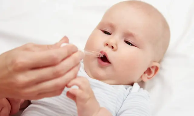 Ein Baby erhält Tropfen mit Vitamin D und Fluorid.