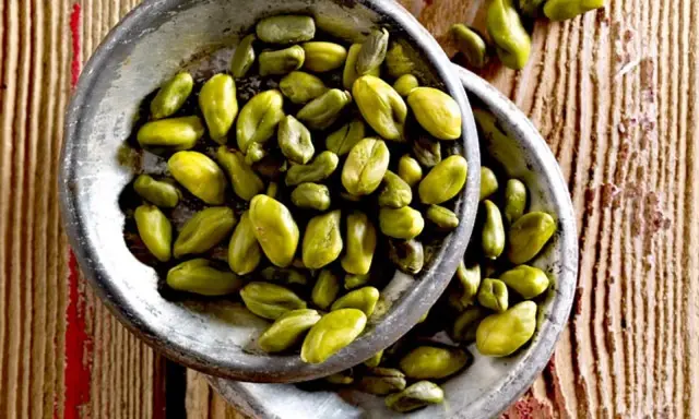 Grüne Pistazienkerne in zwei Schalen auf Holzuntergrund. Diese gesunden Pistazien sind ein leckerer Snack.