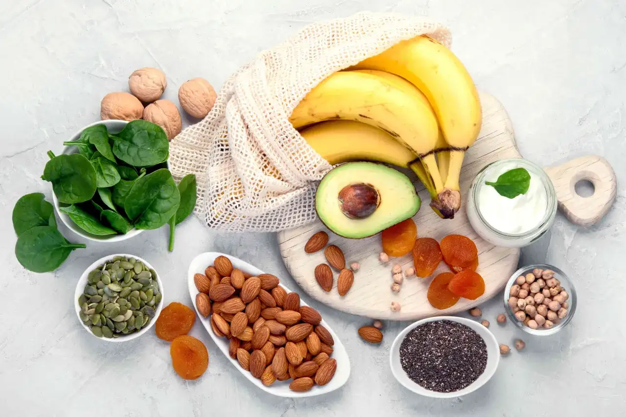 Bananen, Spinat, Mandeln, Aprikosen und Kürbiskerne: eine Auswahl an Lebensmitteln mit Kalium für eine gesunde Ernährung.