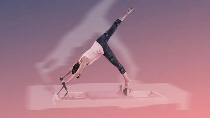 Frau in der Pose "Herabschauender Hund" auf einem Reformer Pilates Gerät.